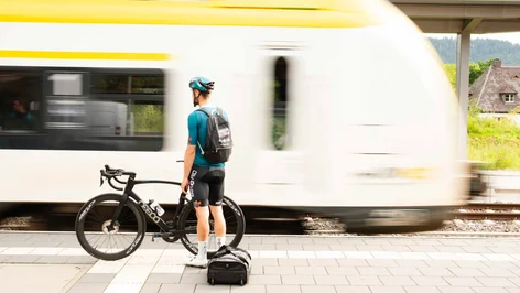 Fahrgast mit Fahrrad vor vorbeifahrendem Zug am Bahnsteig