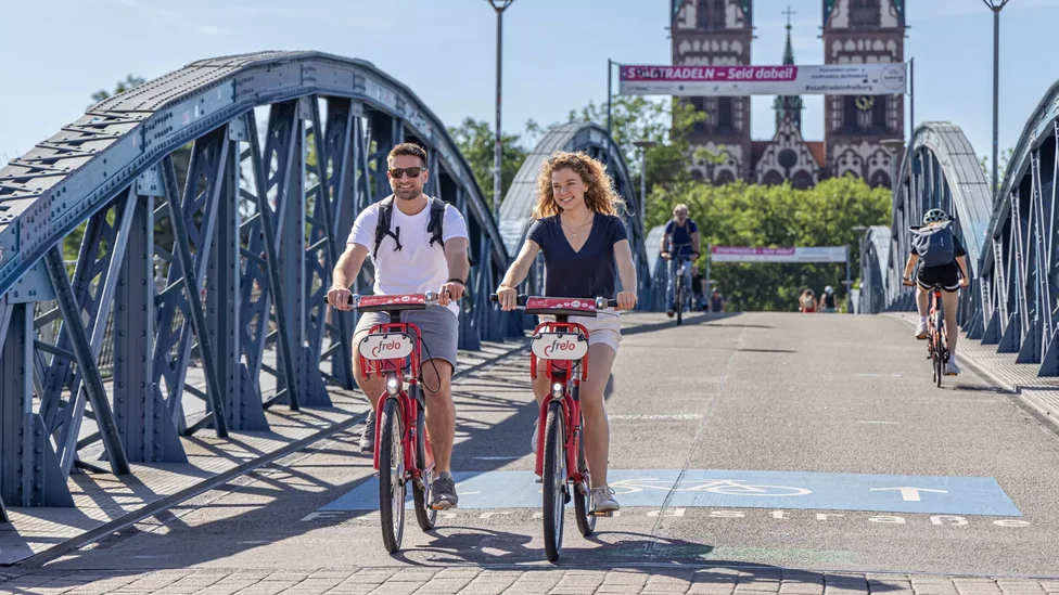 Zwei Fahrradfahrer radeln auf Frelo-Rädern über die Wiwili-Brücke in Freiburg