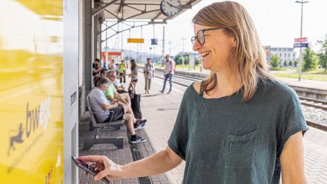 Frau an Fahrscheinautomat